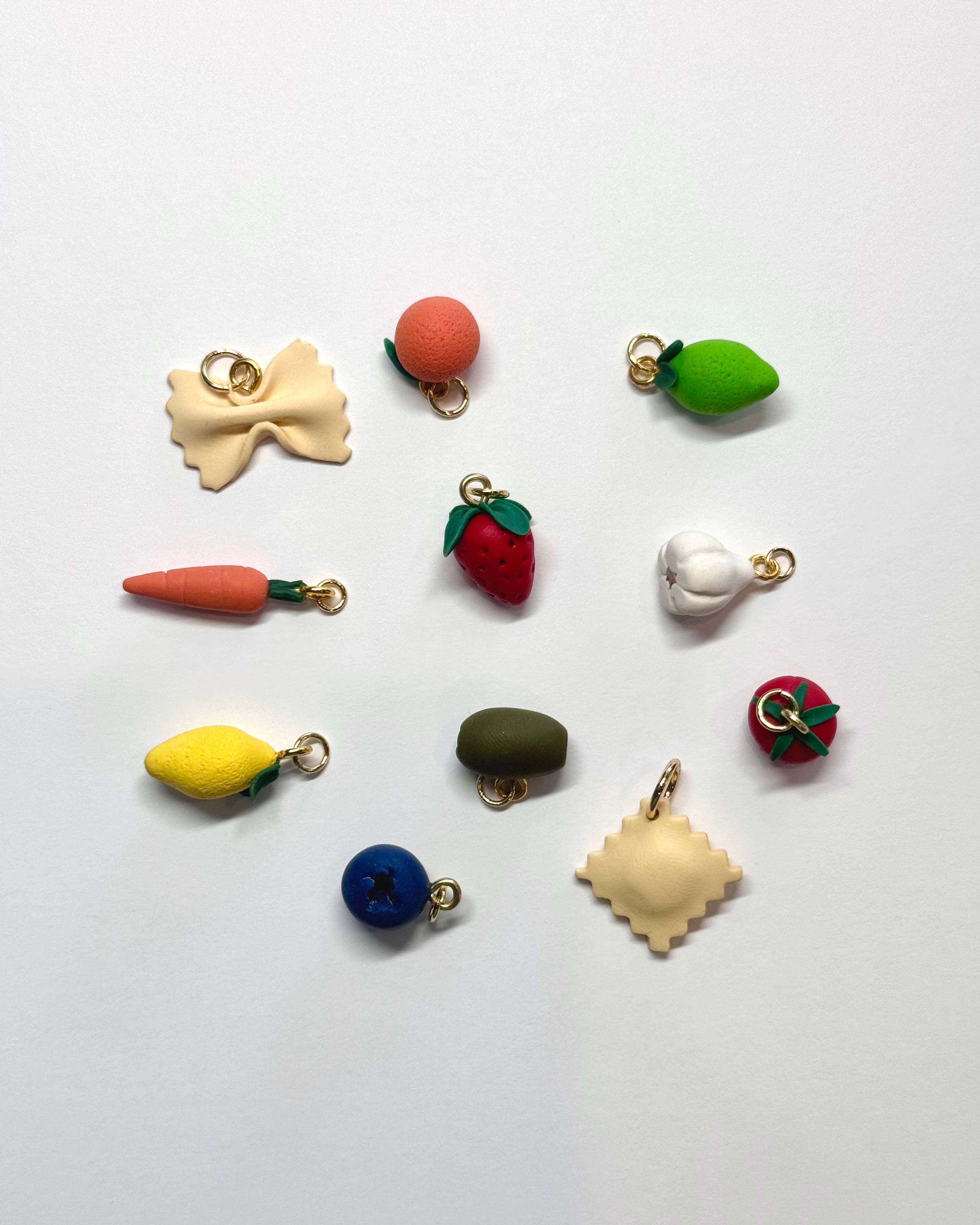 Colorful miniature fruit, vegetable and pasta charms on a white background